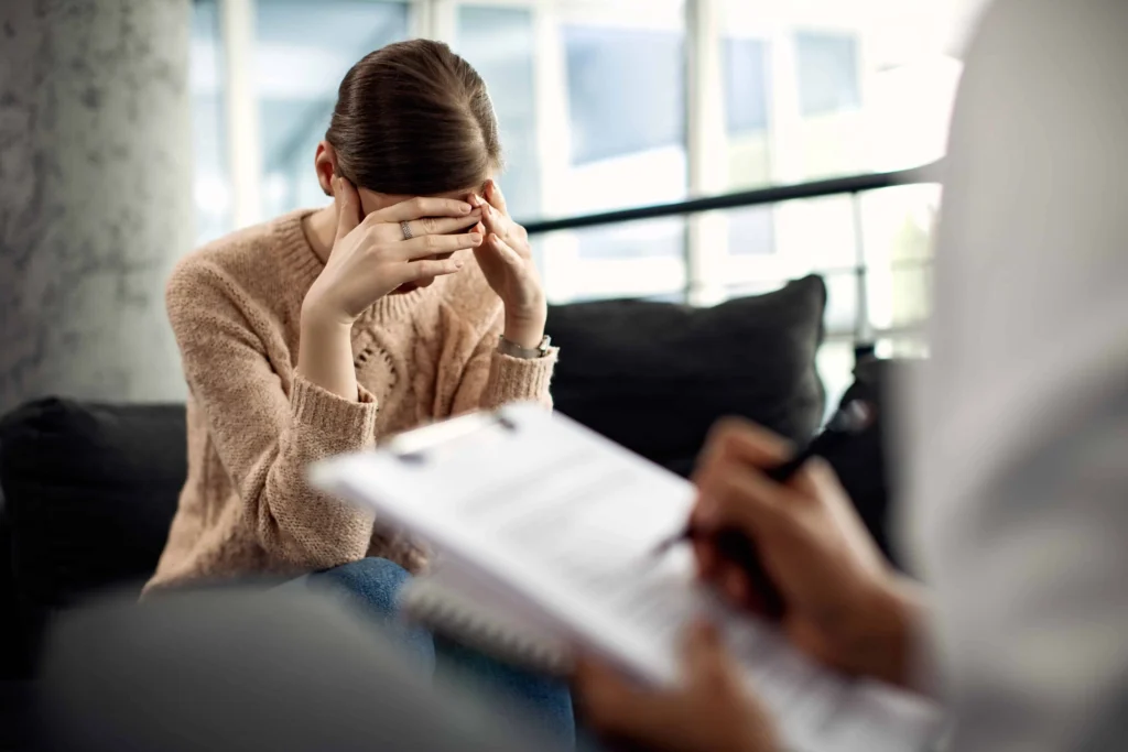 Mulher em sessão de psicoterapia demonstrando sofrimento emocional em um ambiente de acolhimento profissional.